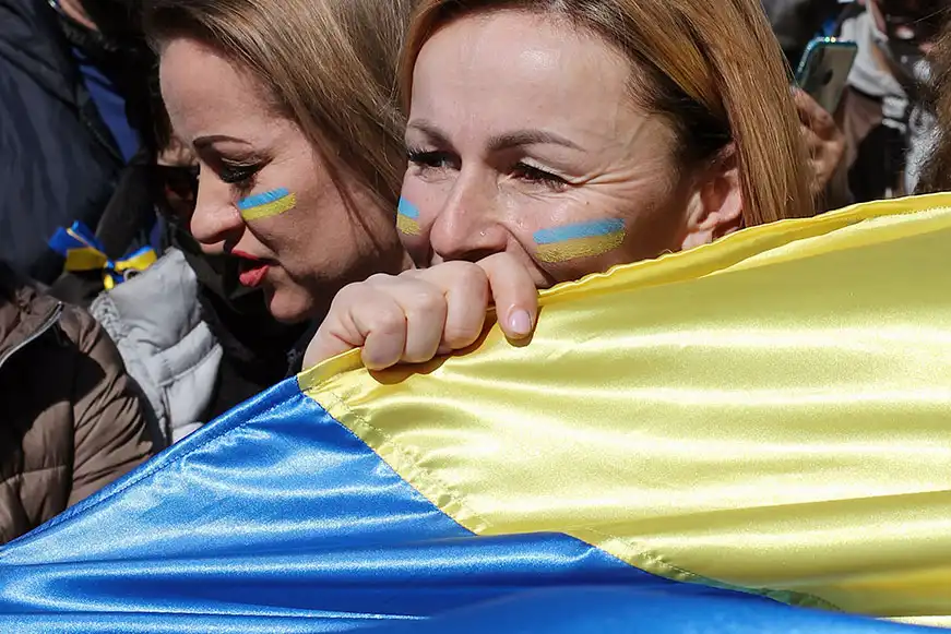 Woman holding a large Ukraine flag close to her face